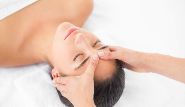 Vue de côté d'une jeune femme attirante recevant un massage de la tête dans un centre de spa